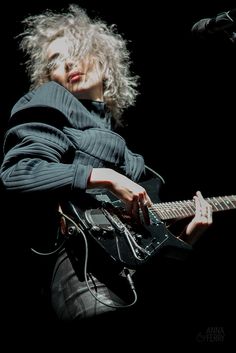 a woman with blonde hair playing an electric guitar