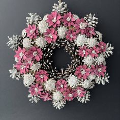 a pink and white wreath with snowflakes hanging from it's sides on a gray background