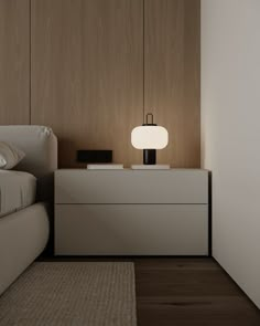 a white bed sitting next to a night stand with a lamp on top of it