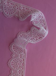 a white lace ribbon on a pink background