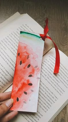 a bookmark with watermelon painted on it and a red ribbon tied around it