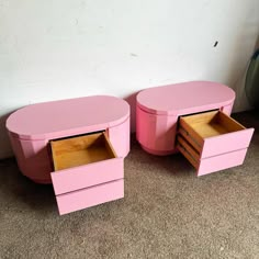 two pink tables sitting next to each other on top of a carpeted floor in front of a white wall