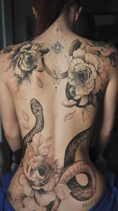 the back of a woman's body with flowers and snakes on it