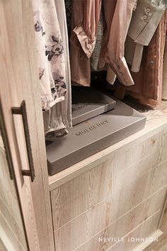 an open closet with clothes hanging on hangers