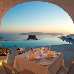 an outdoor dining area with table and chairs overlooking the ocean at sunset or sunrise,