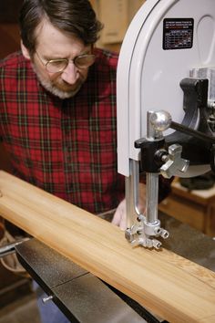 a man working on a piece of wood with a machine in front of him and looking at it