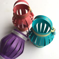 three different colored paper lanterns sitting on top of a white table next to each other