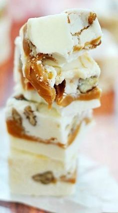 three pieces of dessert stacked on top of each other with white frosting and caramel toppings