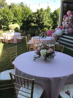 a table set up with balloons and flowers for a wedding or other function in the backyard