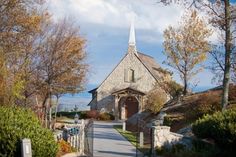 an old stone church with a steeple on the top is surrounded by trees and shrubs