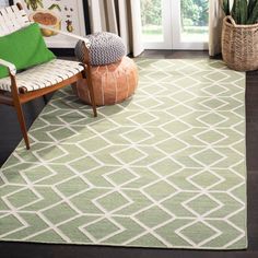 a green and white rug in a living room next to a chair with a potted plant