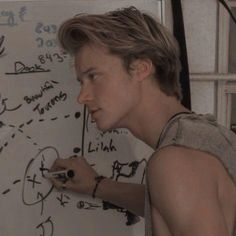 a young man writing on a white board