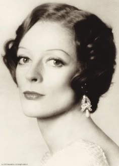 an old black and white photo of a woman with big earrings on her head, looking off to the side