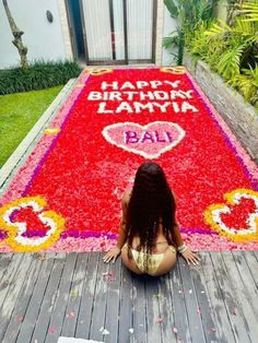 a woman sitting on top of a wooden floor next to a red and yellow birthday mat