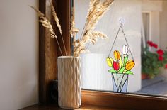 a vase filled with flowers sitting on top of a window sill next to a flower pot