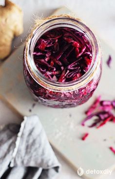 a jar filled with red cabbage sitting on top of a cutting board