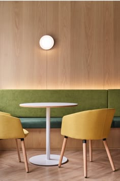 two yellow chairs and a white table in a room with wood paneling on the walls