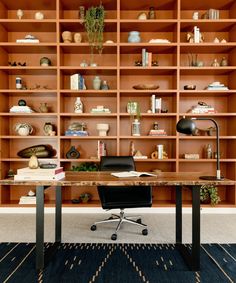 an office with wooden shelves and black chair