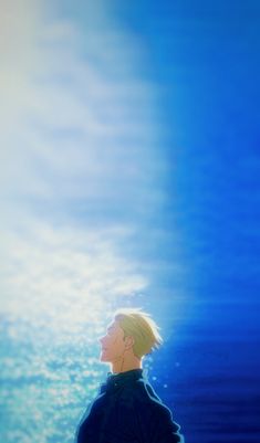 a man standing in front of the ocean with his back to the camera and looking up