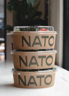 three plastic containers filled with food sitting on top of a white counter next to a potted plant