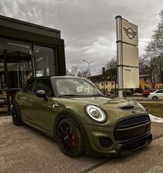 a small green car parked in front of a building