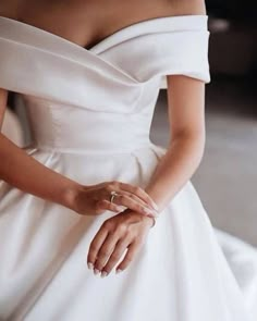 a woman in a white wedding dress with her hands on her hip and wearing a ring