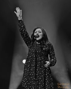 a black and white photo of a woman on stage with her hands in the air