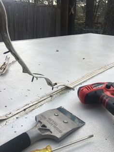 some tools are laying on top of a white surface with trees in the back ground