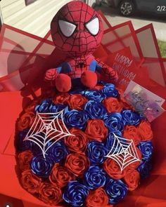 a spiderman cake with red, white and blue roses in the shape of roses