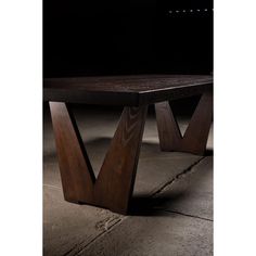 a wooden table sitting on top of a cement floor next to a black wall in the dark