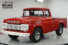 an old red pick up truck parked in a garage