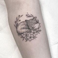 a tattoo with a fox and flowers on the left side of the arm, it is black and white