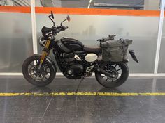 a black motorcycle parked in front of a glass wall with yellow lines on the floor