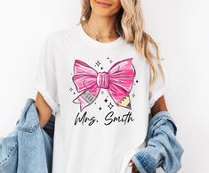 Retro Coquette Pink Pencil Bow Back To School Teacher Gift Shirt with custom name is perfect for any teacher this year! Customize with her name!The pink is featured on a short sleeve trendy Comfort Color tee, White and Ivory are Bella Tees ✨ HOW TO ORDER ✨✧ Select Options from the Drop Downs✧ Record personalization requests✧ ADD TO CART 🎨 GRAPHIC DETAILS 🎨► Professionally and Permanently Printing Process► Vibrant and Accurate colors► No Vinyl Used► Soft Print Water-Based Inks - NOT PLASTICY OR Pink Short Sleeve Tops For School Events, Pink Short Sleeve T-shirt For School Events, Pink Custom Print T-shirt For School, Pink Teacher Shirt, Back To School Pink Graphic Print T-shirt, Summer Short Sleeve T-shirt With Pink Bow, Pink Short Sleeve T-shirt With Bow, Cute Cotton T-shirt With Pink Bow, Thanksgiving Wedding