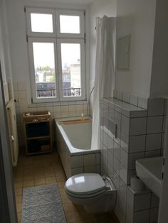 a bathroom with a bathtub, toilet and rug in the floor next to it