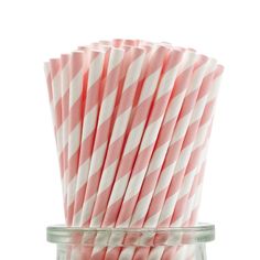 several pink and white striped paper straws in a glass jar on a white background