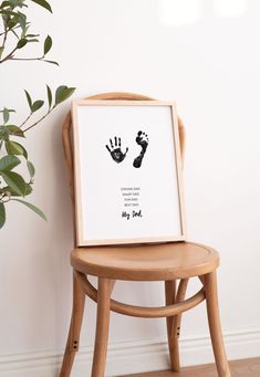 a wooden chair sitting next to a white wall with a black handprint on it