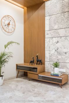 a living room with a clock on the wall next to a wooden table and plant