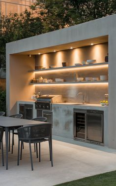 an outdoor kitchen is lit up at night with lights on the wall and cabinets above it