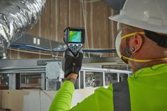 a man in safety gear is looking at something on the screen while wearing a hard hat