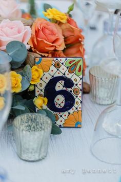 the table is decorated with colorful flowers and glassware, including an artistic card holder