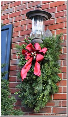 a christmas wreath hanging on the side of a brick building next to a street light