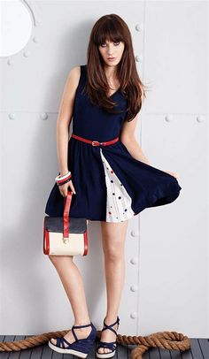 a woman standing on top of a wooden floor holding a handbag and wearing sandals