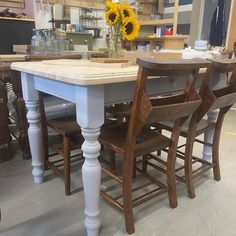 a kitchen table and chairs with sunflowers on the counter in front of it