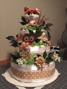 a three tiered cake decorated with an owl, deer and flower arrangement on top