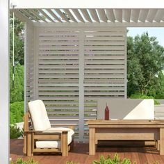 an outdoor living area with wooden furniture and white privacy screens on the side of the building