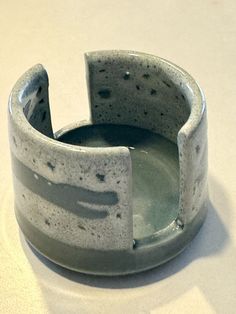 a gray and white bowl sitting on top of a table next to a black object