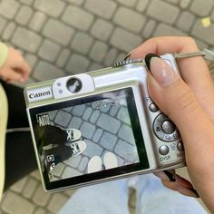 a person holding up a camera to take a picture on the street with their feet