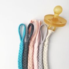 four different colored ropes with a hook on it's end and an object in the middle