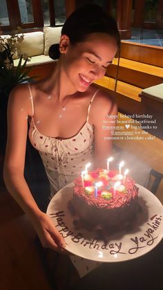 a woman holding a birthday cake with lit candles